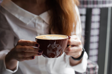 Woman holding cappuccino coffee cup