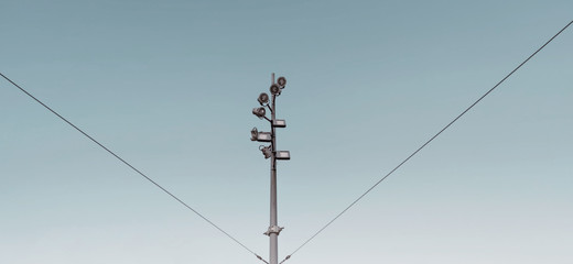 Modern metal pole street , gray with multiple spot light , cables holding up, blue background, Amsterdam, Feb 2020. 