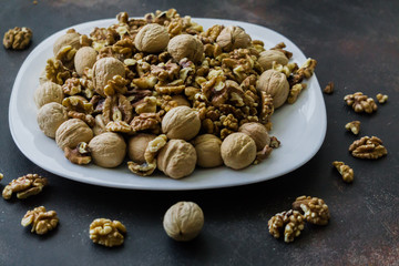 Walnuts peeled and in shells on a table in a plate.