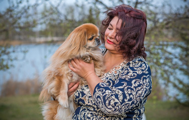 Woman with a  dog is a human best friend. Pekingese light red color resting with his owner enjoying the life