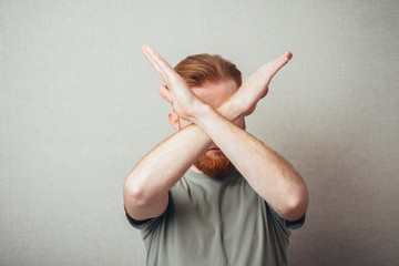 Serious and determined Young hipster red bearded Man makes an X shape with his arms and hands. stop, cross, or - obrazy, fototapety, plakaty