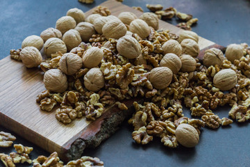 Shelled and shelled walnuts on a wooden board on the table. Healthy nutrition, vegetarianism, diet.