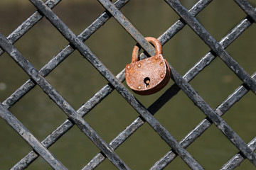 Old rusty padlock on a black fence on a street in sunny weather minimalism horizontal photo