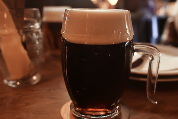 mug of dark beer in the interior of  pub / pint of beer with foam on a served table in  beer restaurant in Czech Republic