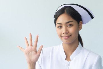 portrait of serious asian woman nurse isolated pointing 5 fingers to blank space; confident and professional female nurse or medical worker pointing five finger up, five points or fifth point