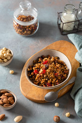 Healthy breakfast with muesli. Cereal granola with fruits, berries and nuts in a bowl on gray concrete background. Side view, vertical