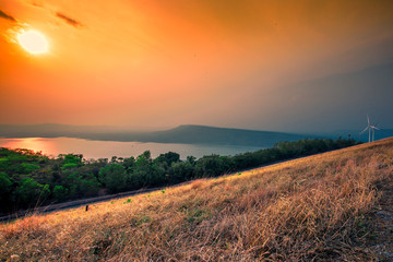 Natural panoramic nature background,high angle viewpoint area, overlooking trees, mountains, large wind turbines,cool wind blurring, abundance of forest