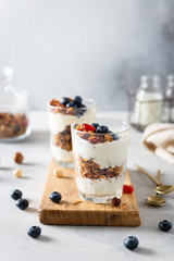 Crunchy honey granola with yogurt in glasses on white background. Dry breakfast cereals with flax...