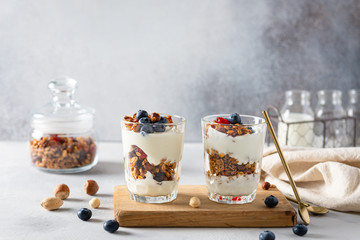 Crunchy honey granola with yogurt in glasses on white background. Dry breakfast cereals with flax seeds, cranberries and nuts. Healthy, vegeterian fiber food. Breakfast time. Dieting. Copy space