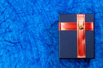 A blue gift box with red ribbon and a heart sticker on it. Wedding gift concept.
