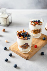 Crunchy honey granola with yogurt in a glass on gray background. Dry breakfast cereals with flax...