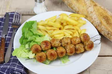 brochettes de poulet et frites dans une assiette
