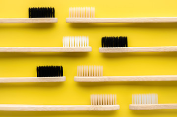 Zero waste concept. Group of eco natural bamboo toothbrushes on a bright yellow background. Flatlay, horizontal orientation. Layout natural organic hygiene products. no plastic