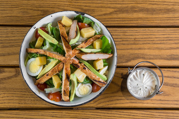 Top view of a fresh salad with dressing aside