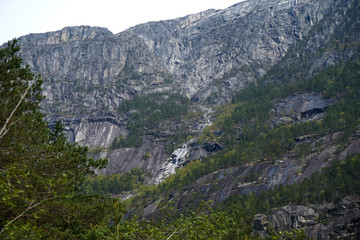 Fototapeta na wymiar Small waterfall in the forest, between the mountains in Norway.