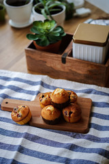 Obraz na płótnie Canvas Muffins with cranberries and chocolate are beautifully laid out on the cutting Board, around the atmosphere of home and comfort, beautiful interior, natural wood, a Cup of tea