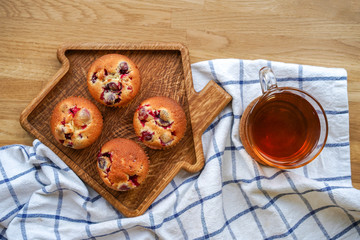 Muffins with cranberries and chocolate are beautifully laid out on the cutting Board, around the atmosphere of home and comfort, beautiful interior, natural wood, a Cup of tea