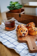 Muffins with cranberries and chocolate are beautifully laid out on the cutting Board, around the atmosphere of home and comfort, beautiful interior, natural wood, a Cup of tea