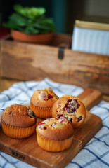 Muffins with cranberries and chocolate are beautifully laid out on the cutting Board, around the atmosphere of home and comfort, beautiful interior, natural wood, a Cup of tea