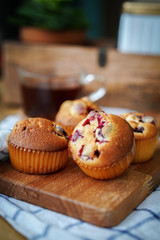 Muffins with cranberries and chocolate are beautifully laid out on the cutting Board, around the atmosphere of home and comfort, beautiful interior, natural wood, a Cup of tea