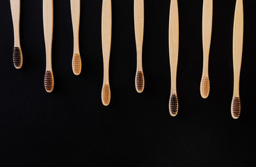 Group of eco bamboo toothbrushes, on black background. Different color. Top view, copy space. Natural organic product for oral hygiene. Dental zero waste and no plastic concept. Safe for the earth.