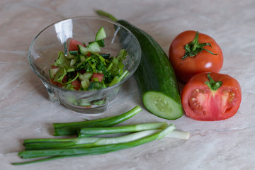 Vegetable salad in a transparent plate. sliced cucumber, tomato, pepper and green onion.