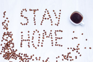 Coffee beans, cup of coffee on white wooden background, stay at home concept.