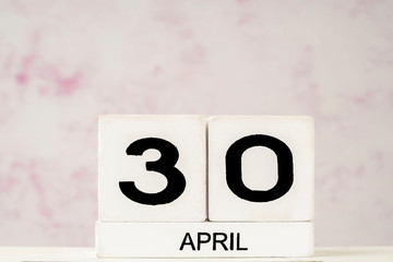 White cube calendar for April over pink background with copy space