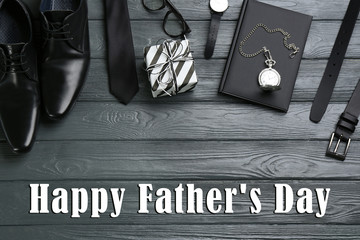 Flat lay composition with male accessories and phrase HAPPY FATHER'S DAY on grey wooden background