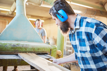 Carpenter apprentice with hearing protection with wooden board