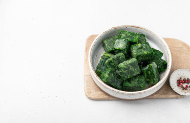 frozen spinach in a ceramic bowl on a light background, top view