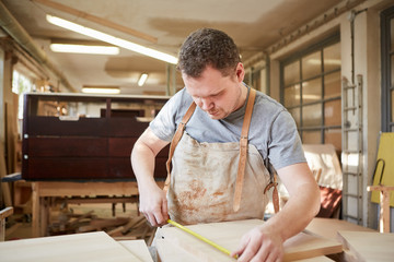 Carpenter apprentice measuring wood
