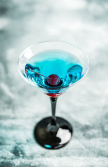 Blue martini cocktail with cherry on the rustic background. Selective focus. Shallow depth of field.
