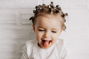 Portrait of a girl with bright sincere baby emotions. Little curly girl posing for a photo