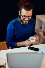 Attractive Caucasian bearded entrepreneur sitting in his home office, taking a break from work. Work from home concept.