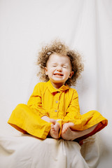 Portrait of attractive cute baby dressed in yellow dress posing on light background in home improvised photo studio
