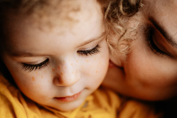 mom and daughter. Attractive young mother and her fragile curly baby girl hugging and having fun...