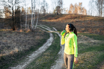 Fototapeta premium Young woman in sportswear outdoors drinks water