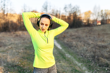 Naklejka premium Young woman in sports wear with earphones outdoors