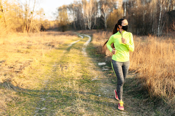 Woman in medical mask is jogging outdoors