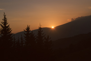 Naklejka premium wonderful orange sunset in mountains during the hike