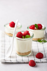 cheesecake in a glass decorated with raspberries and mint on a gray background