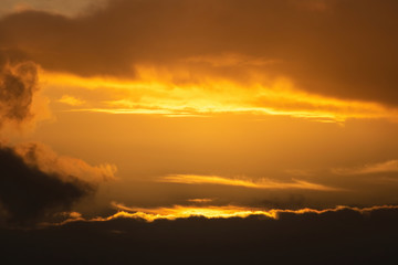 Aerial view of gap in dark clouds lit by sunset light