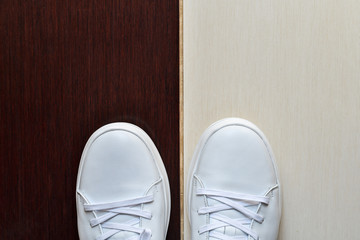 White casual sneakers on light beige and brown tile background. Copy space.