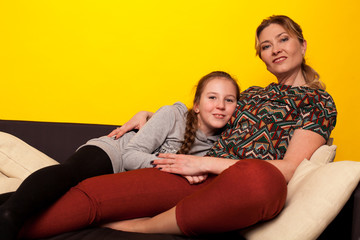 Mom and daughter sit at home in a room on the family couch