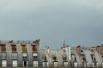 Paris city roofs, chimneys and mansards. European lifestyle, city residents self isolation. Typical old Paris architecture, facades of residential buildings, expensive real estate concept