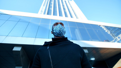 African American man out and about in the city streets during the day, wearing a face mask against...