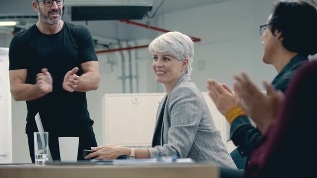 Team of corporate professional clapping hands in a meeting. Business people appreciating the efforts and contribution of a mature businesswoman for the company.
