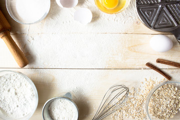 Eggs, sugar, flour, oatmeal, cinnamon, whisk, rolling pin on vintage wooden background. Cooking dessert flat lay top view with copy space. Baking ingredients for homemade pastry. Stock photo.