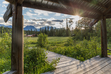 wooden porch of a canada farm on a green grassy meadow, sunny day